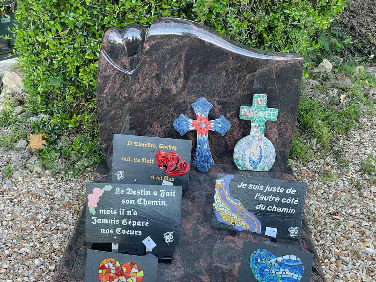 Tombe décorée de plusieurs plaques commémoratives et de croix en mosaïque colorée