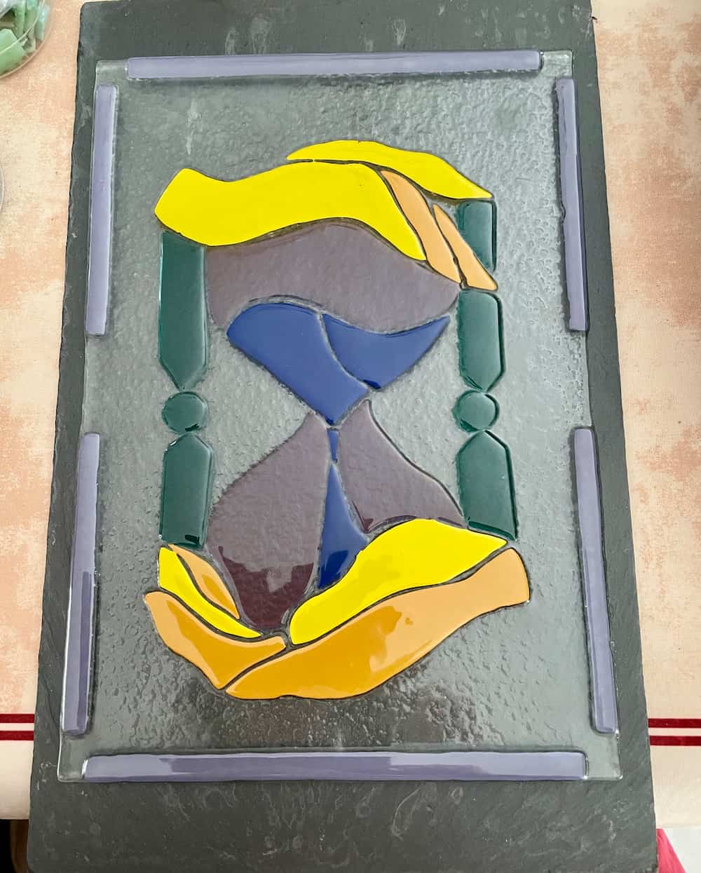 Mosaïque artistique représentant un sablier stylisé avec du sable s'écoulant entre les deux compartiments