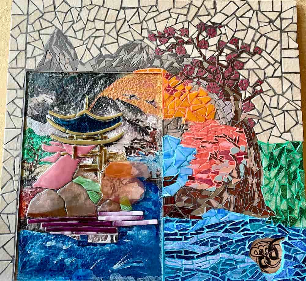 Mosaïque représentant un paysage japonais avec un torii, un arbre fleuri, des montagnes et un coucher de soleil vibrant sur fond de rivière