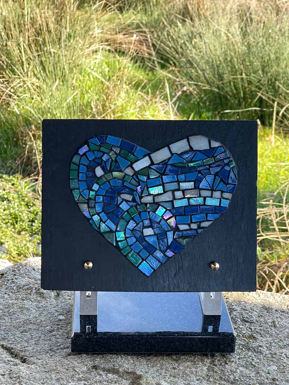 Plaque funéraire en forme de cœur de couleur bleue, posée sur un support, symbolisant le souvenir et l’amour éternel