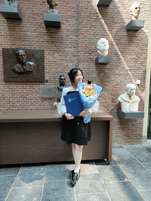 Young woman holding a bouquet and a diploma.