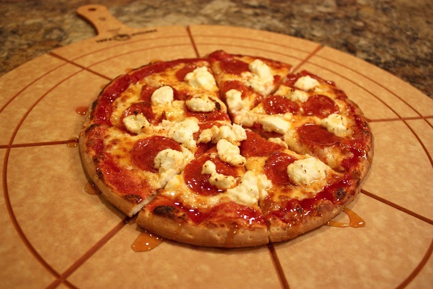 A freshly cut pizza rests on a pizza cutter atop a wooden cutting board, showcasing its delicious toppings.