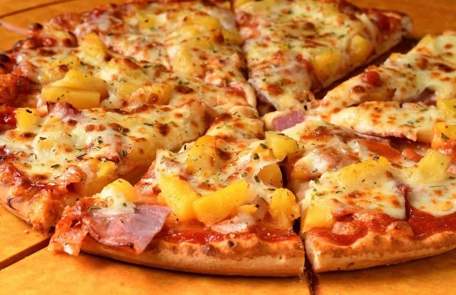 A pizza topped with pineapple and ham, showcasing a blend of sweet and savory flavors.