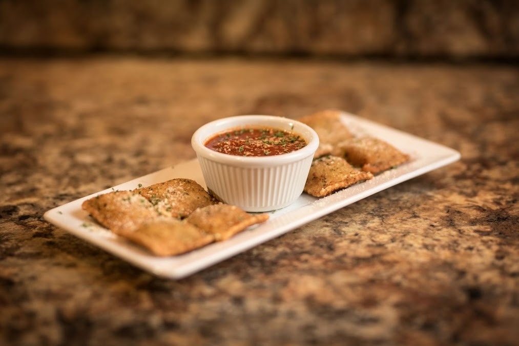A selection of appetizers served on a plate with a small bowl of sauce for dipping.
