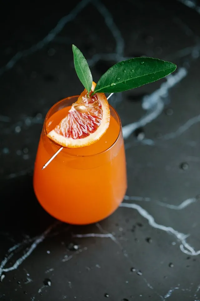 A grapefruit cocktail garnished with a green leaf.