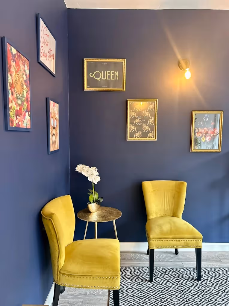 Yellow fabric chairs in a blue room with paintings on the wall