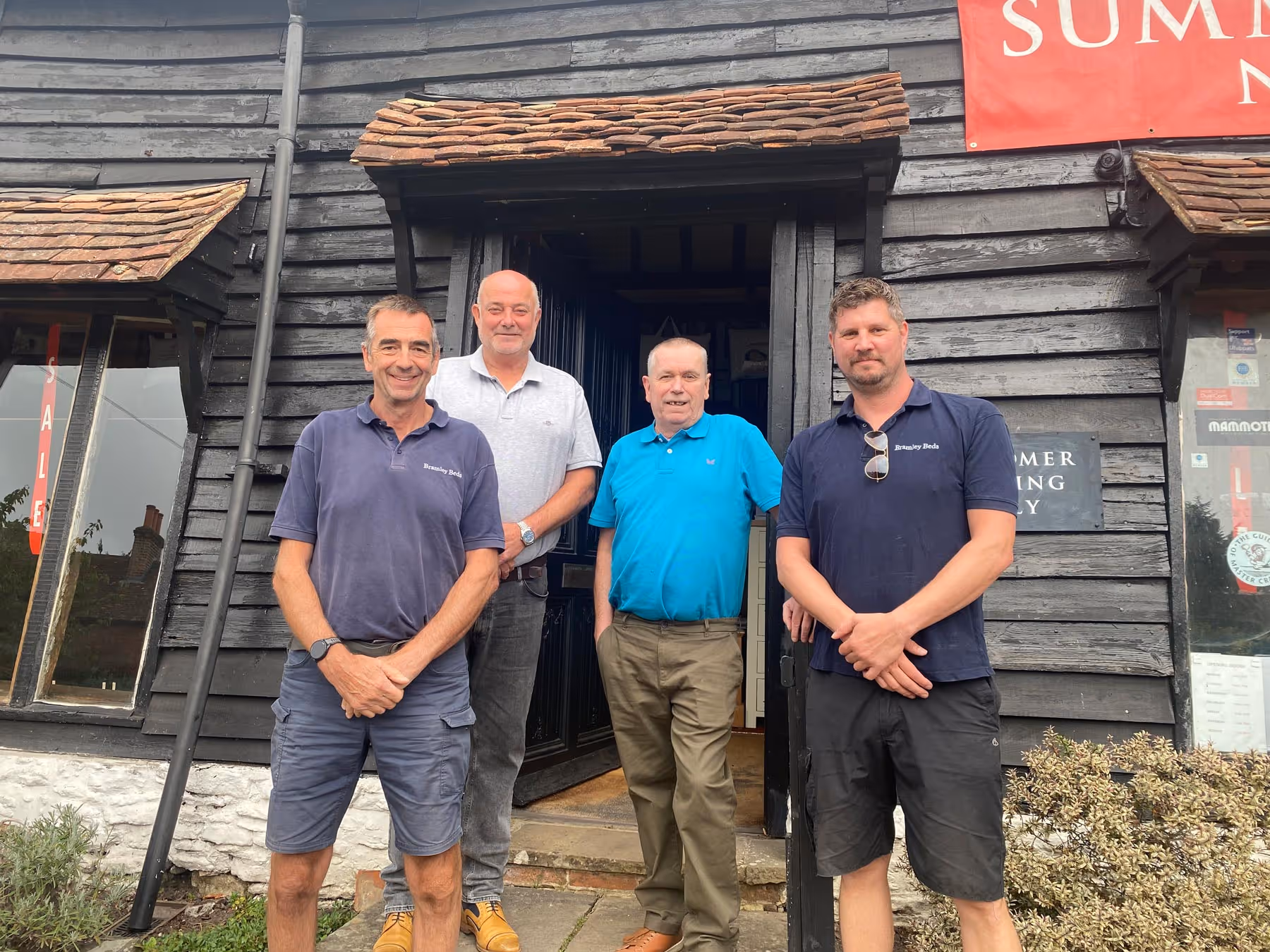 Four men standing outside a wooden clad building in Bramley
