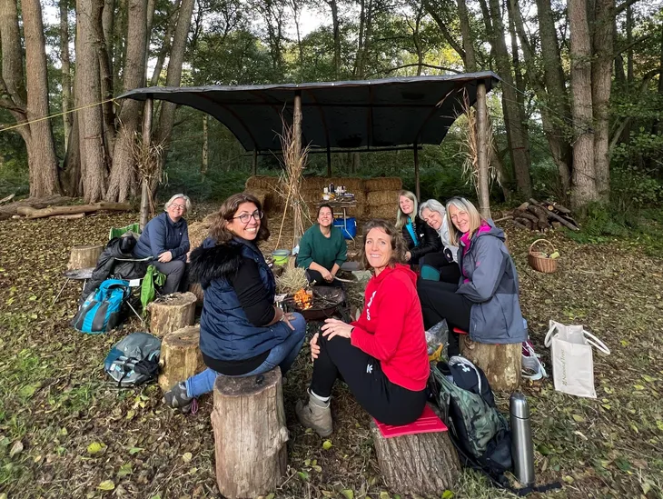Women sat around a fire in woodlands
