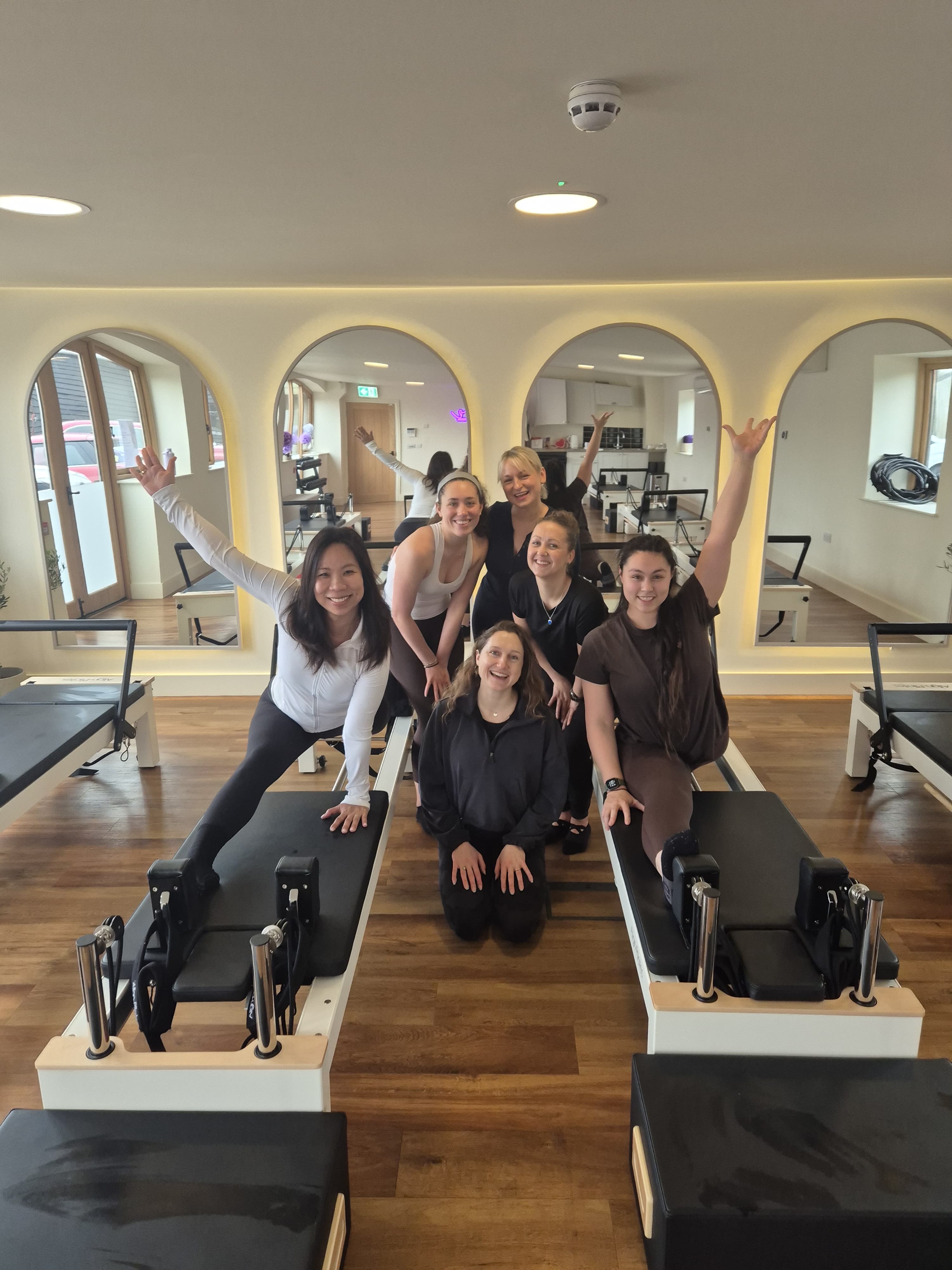 Pilates teachers smiling and waving on reformer equipment