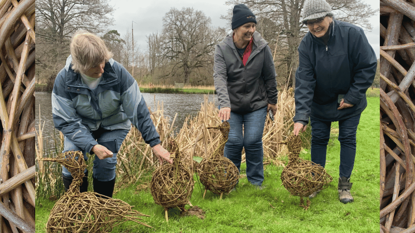 3 women smiling and holding up willow sculptures