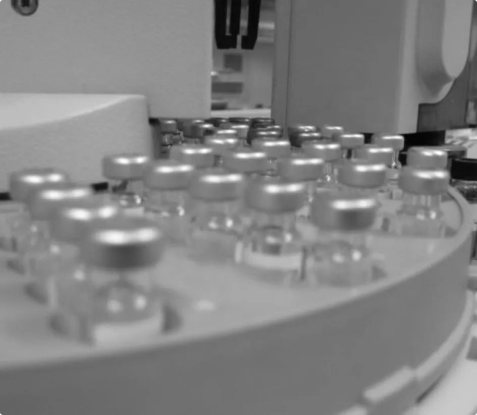 Close-up of multiple small vials with silver caps arranged on a laboratory instrument.