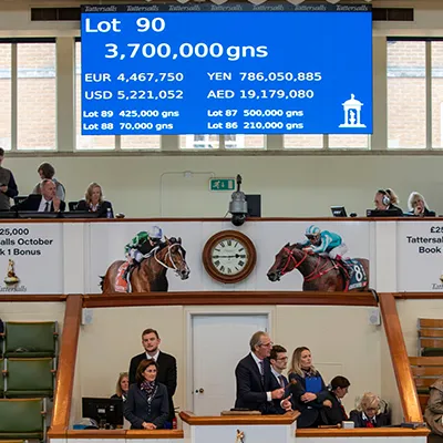 The most expensive yearling's price. Lot 90 sold for 3,700,000 guineas and currency conversions, with people seated below.