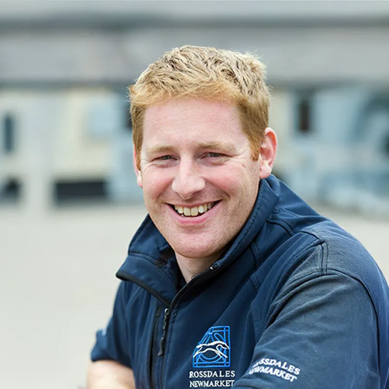 Smiling man with red hair wearing a navy vest with Rossdales Newmarket logo.