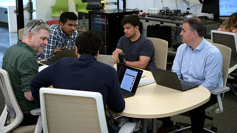 CARNATIONS Researchers collaborating around a table reviewing mobility data on laptops