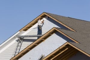 Man installing vinyl siding on a house