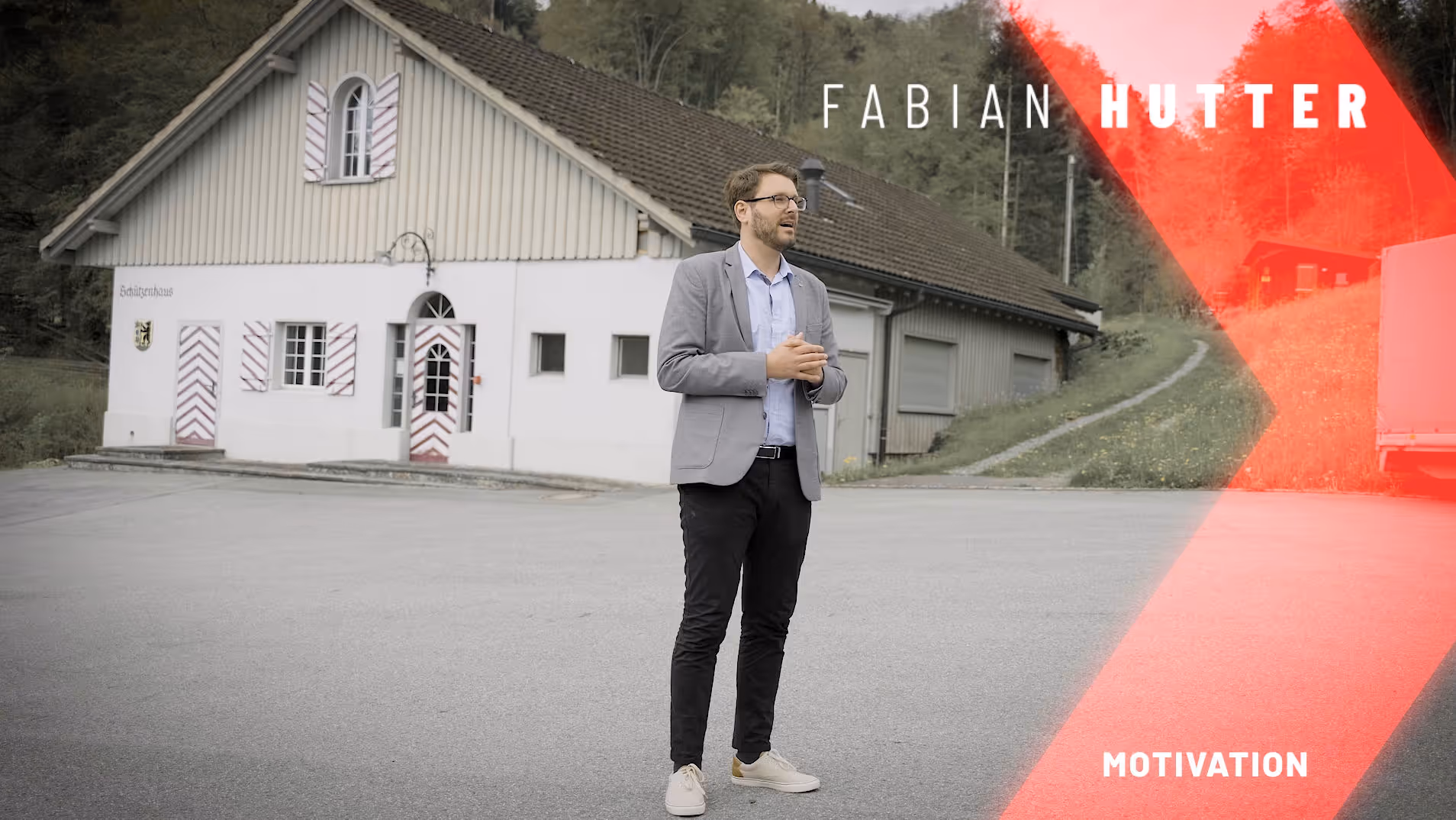 Stehender Mann im Anzug vor einem traditionellen Gebäude im Hintergrund, Text: „FABIAN HUTTER MOTIVATION“.