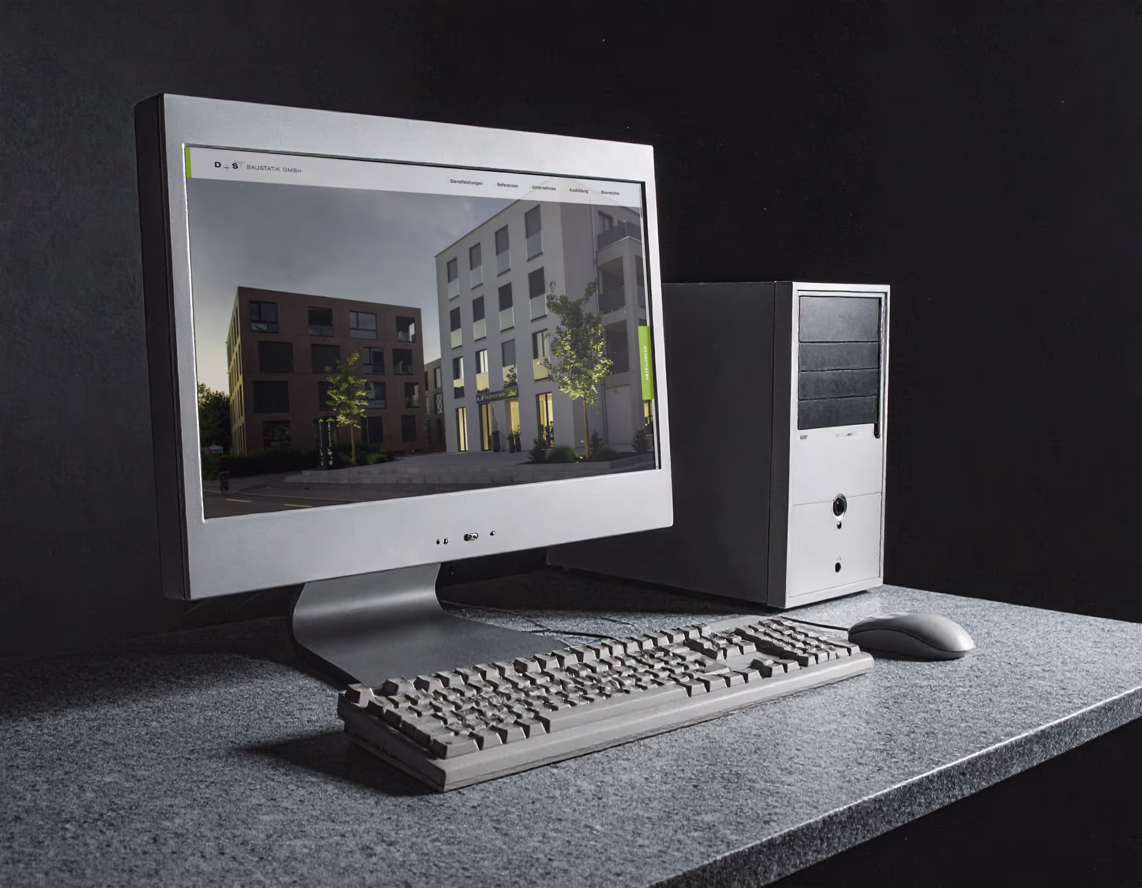 Silberner Röhrenmonitor mit Webseite von D+S Baustatik, die zwei moderne Wohngebäude zeigt, daneben Tastatur und Computer.