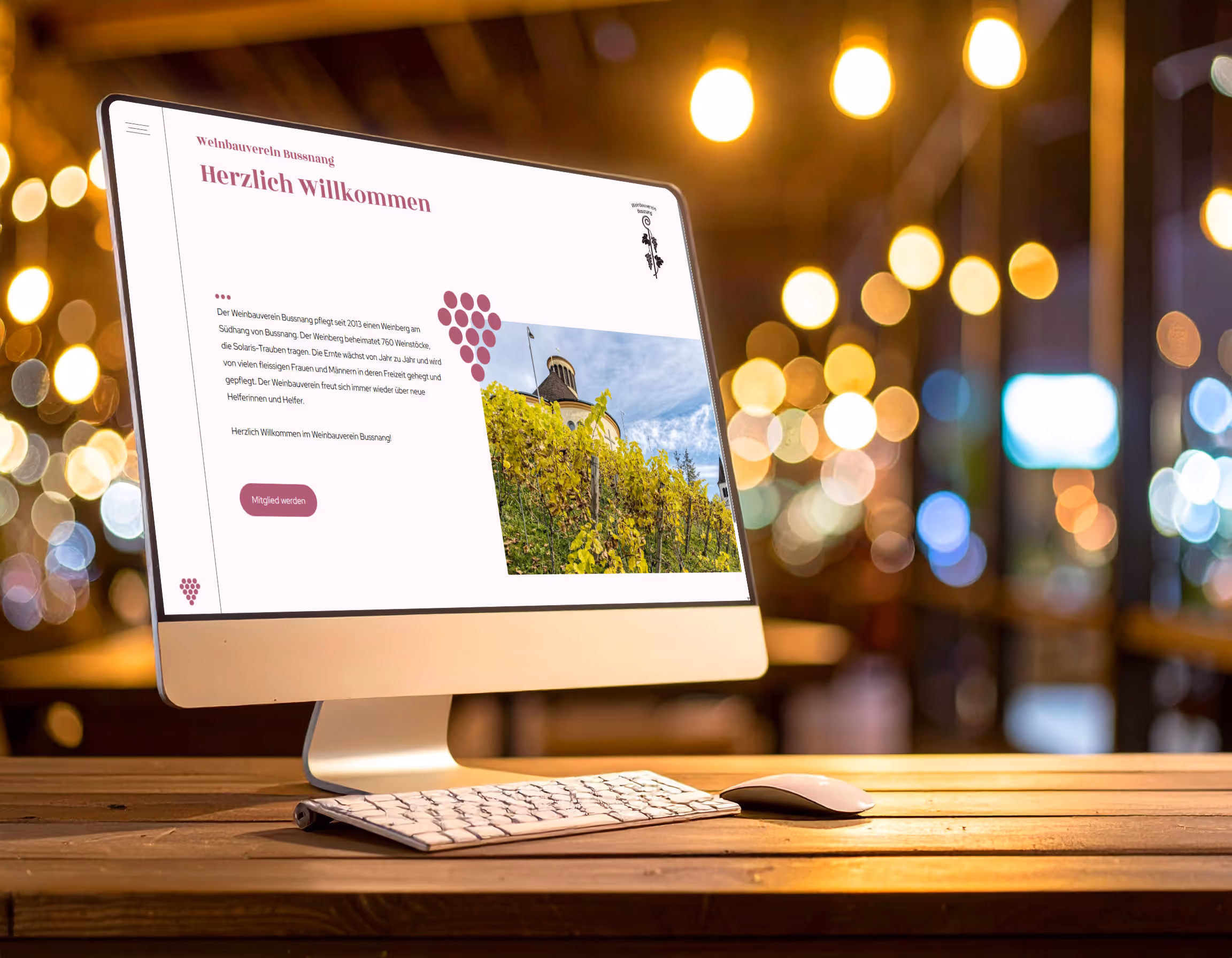 All-in-One-Computer auf Holztisch zeigt die Webseite des "Weinbauverein Bussnang" mit einem Bild von Reben und einer Burg.