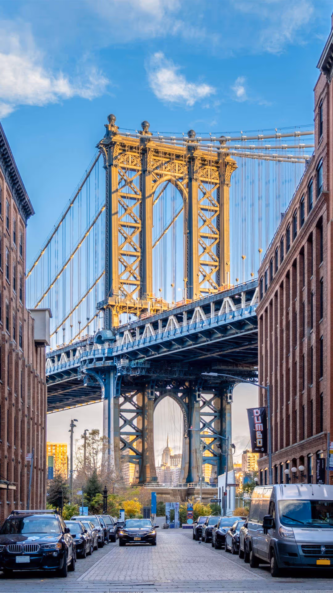 Foto vum Hutter. Die Manhattan Bridge rahmt eine Strasse zwischen hohen Backsteingebäuden in DUMBO, Brooklyn, New York, ein.