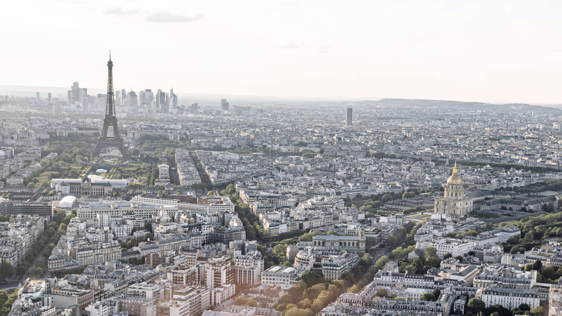 Foto vum Hutter. Breitwinkel-Luftaufnahme von Paris mit dem Eiffelturm, dem Invalidendom und dem Musée de l’Armée in der städtischen Skyline.
