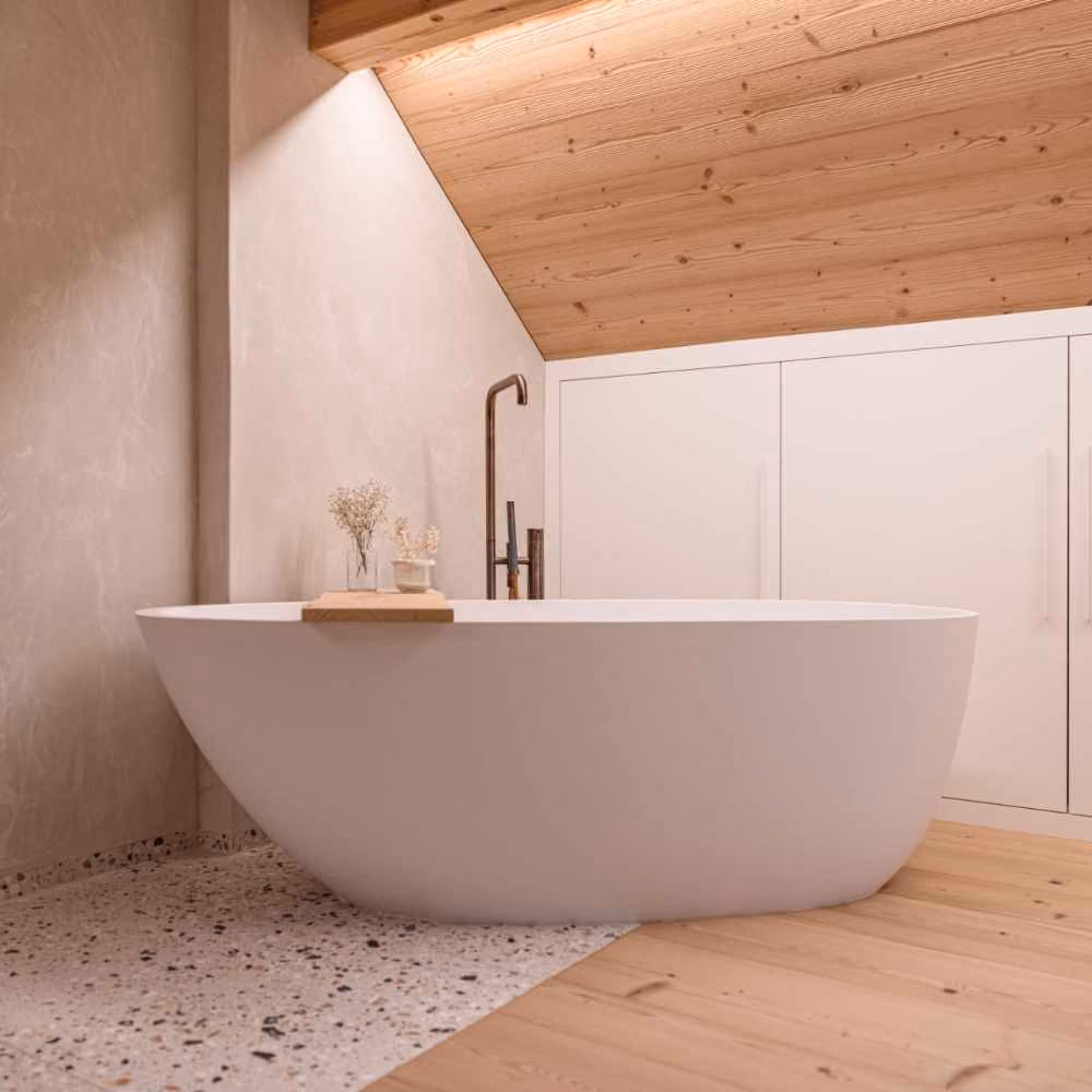 Freistehende, ovale weisse Badewanne in einem modernen Badezimmer mit Dachschräge, Holzboden und weissen Einbauschränken.