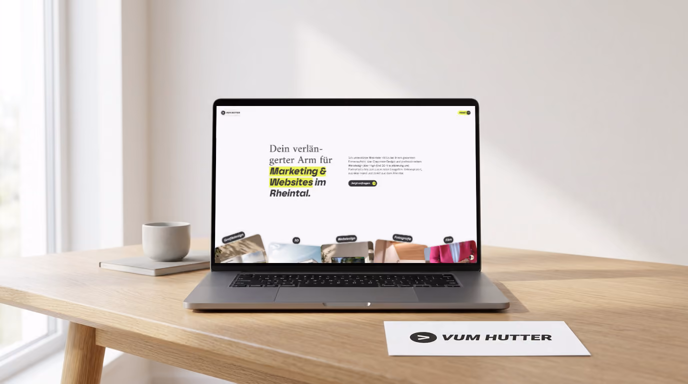 Offener Laptop auf einem Holzschreibtisch mit der Website von „VUM HUTTER“ auf dem Bildschirm und einer Visitenkarte daneben.