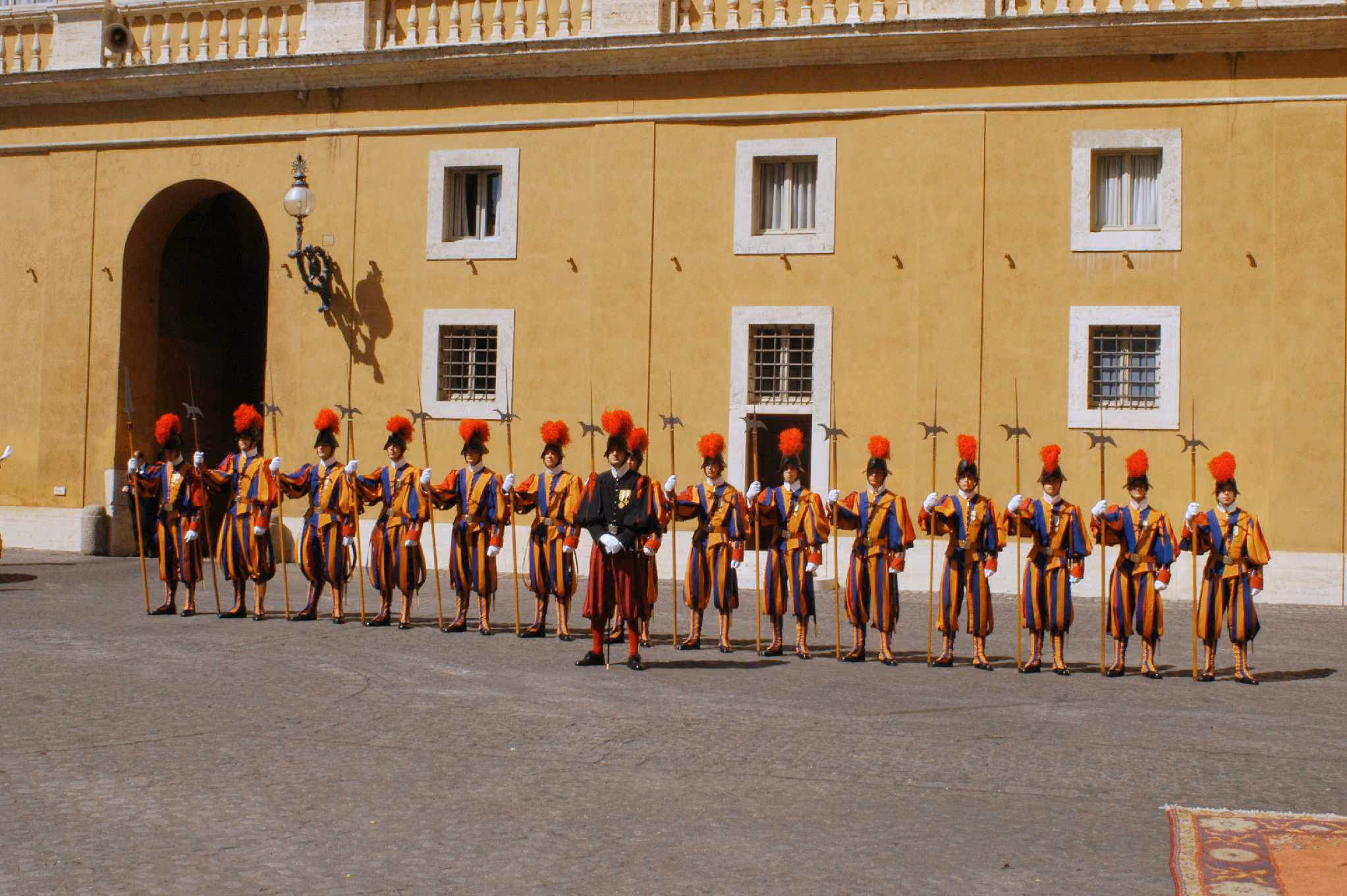 Eine Formation der Päpstlichen Schweizergarde steht in traditioneller Galauniform mit Hellebarden aufgereiht in einem Innenhof des Vatikans.