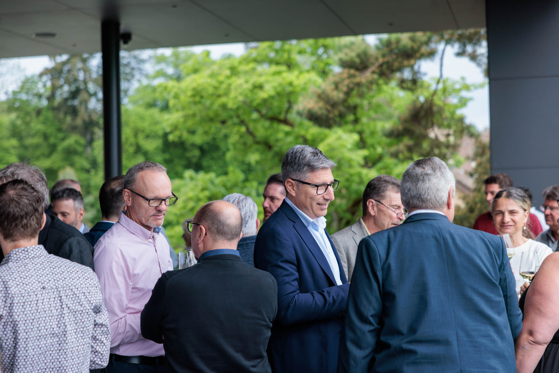 Gruppen im Gespräch beim Apéro unter dem Vordach mit Blick ins Grüne rund um den Wolfsberg