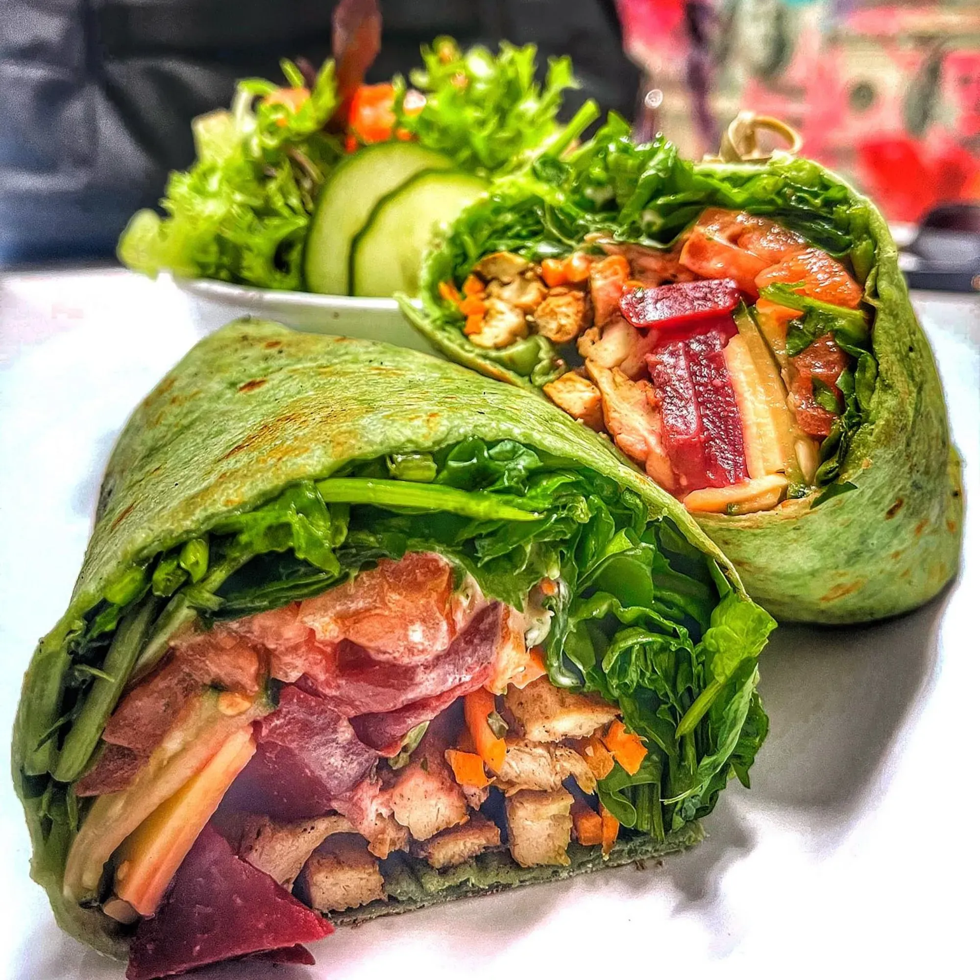 A wrap with meat and vegetables on a white plate.