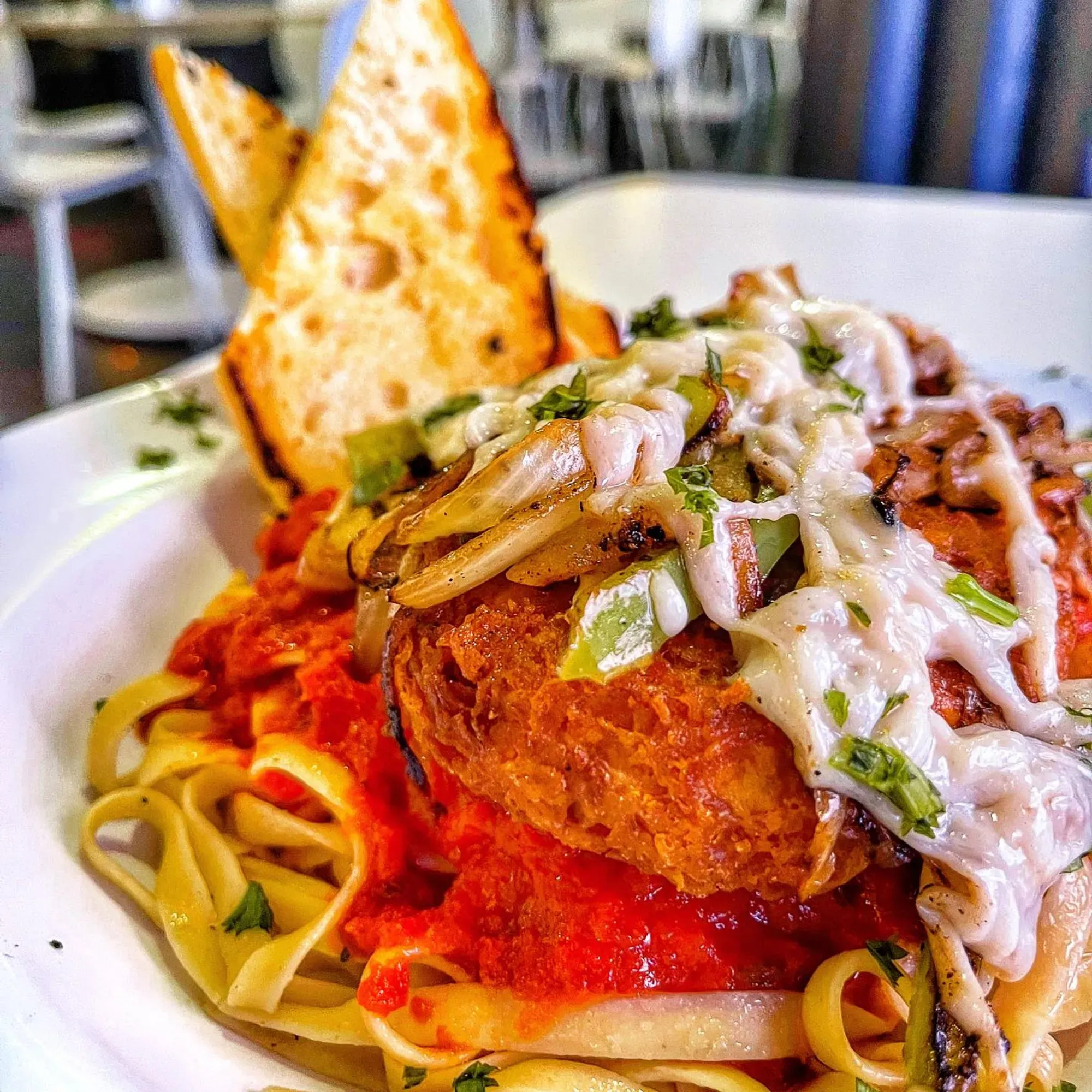 Vegan chicken parm on a bed of linguini with a side of garlic bread
