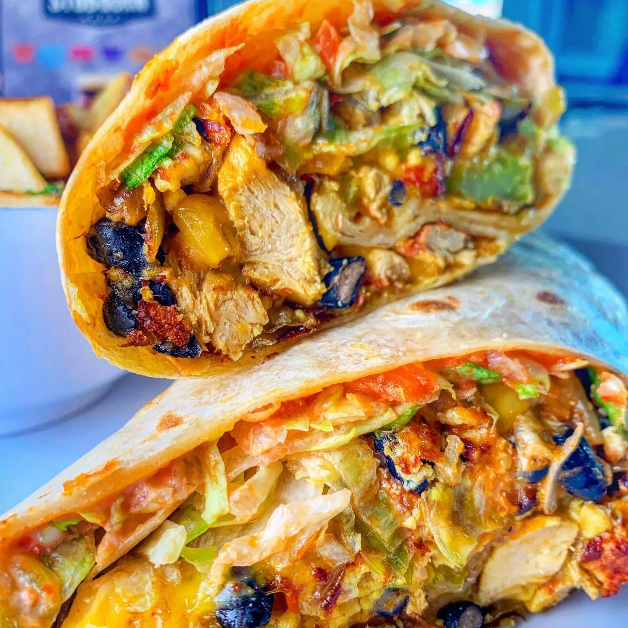 A cross-section of a burrito stuffed with vegan meat and vegetables on a white plate.