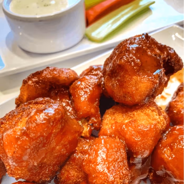 A plate of vegan buffalo chicken wings with a side of carrots and celery.