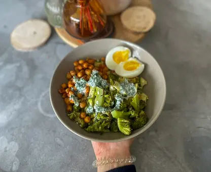 Bol de salade verte aux brocolis et pois chiches tenu à la main, garni d'un œuf dur coupé en deux