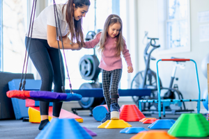 An Occupational Therapist and girl working together in a therapy gym