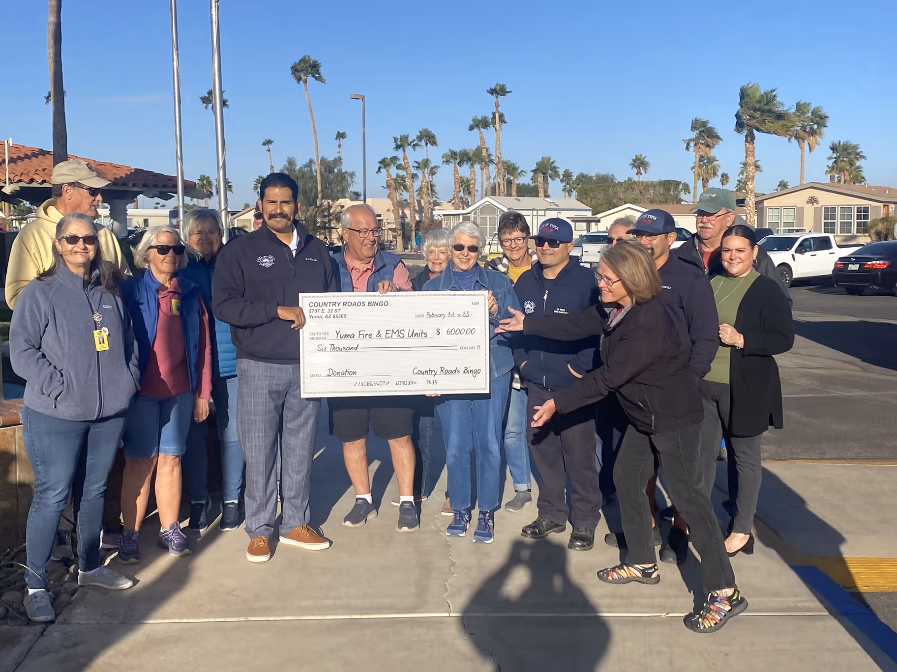 Group photo of community members and firefightesr with large cheeck