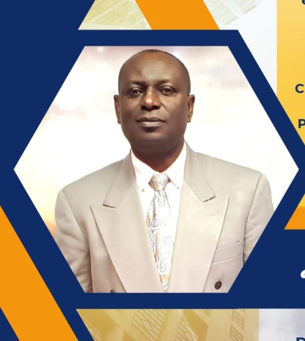 Portrait of a man wearing a light beige suit jacket and a patterned tie inside a hexagonal frame with orange and blue accents.