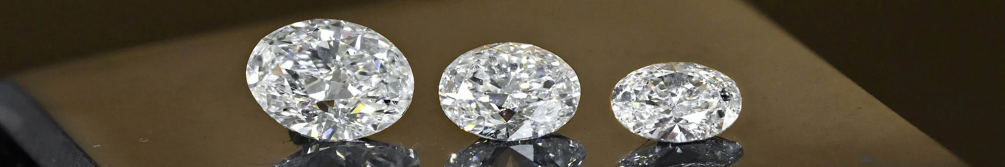 Three round loose diamond stones on a glass table from Jack Lewis Jewelers in Bloomington, IL