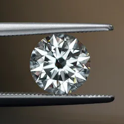close up picture of round diamond being held by tweezers