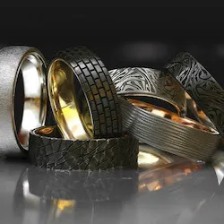 pile of men's wedding bands on a reflective surface