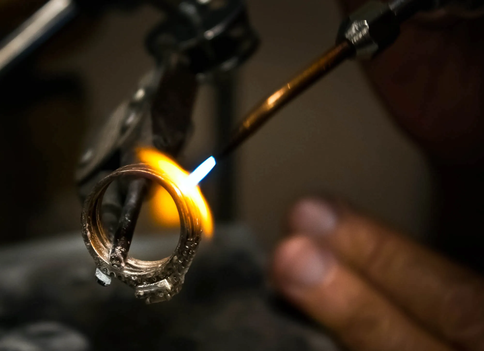 Close up of a man from the jewelry repair shop applying fire to a wedding band.