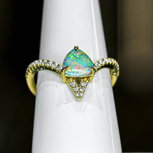 multi colored opal in a rounded triangle shape mounted in a gold ring with diamonds on the band