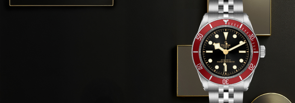 The Black Bay with a burgundy bezel and black dial features a stainless steel bracelet and domed sapphire crystal. Model number M7941A1A0RU-0003 appears on the right side of the screen on a black textured background with gold accents. Jack Lewis Jewelers located at 3011 Galena Rd, Bloomington, Illinois, is proud to be part of the worldwide network of Official Tudor Jewelers, allowed to sell and maintain Tudor Watches.