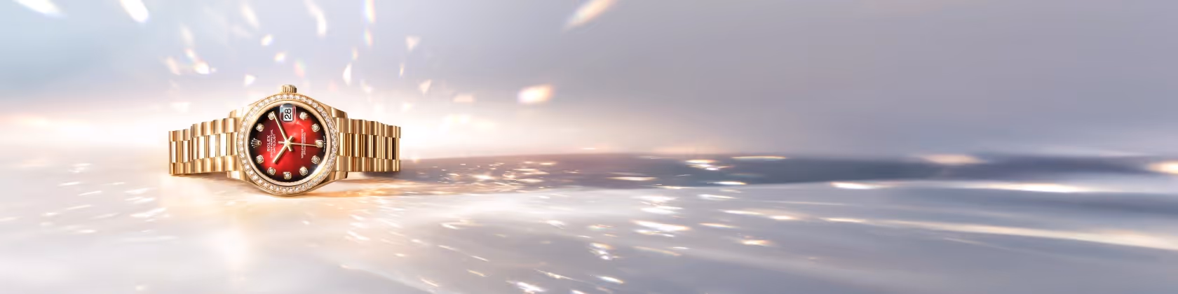 Positioned to the left against a luminous, shimmering backdrop, the Rolex Datejust in yellow gold features a striking red dial illuminated by diamond hour markers. Its elegant profile is enhanced by a diamond-set bezel and the iconic President bracelet, reflecting light in a cascade of warm gold tones. Equipped with the signature date display at 3 o’clock and crafted for precision, reliability, and enduring style, this Datejust embodies timeless luxury. Jack Lewis Jewelers of Bloomington, Illinois, now at 3011 Galena Rd, is proud to be part of the worldwide network of Official Rolex Jewelers.