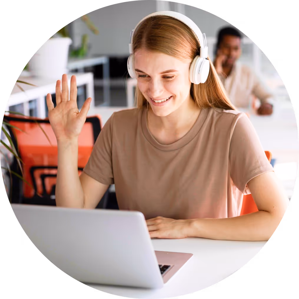 Young woman with headphones waving while video chatting on laptop