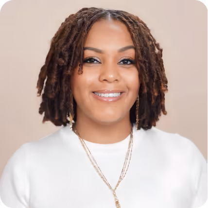 Woman with short dreadlocks wearing white top and necklace