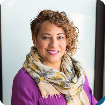 Professional woman in purple jacket and patterned scarf smiling indoors