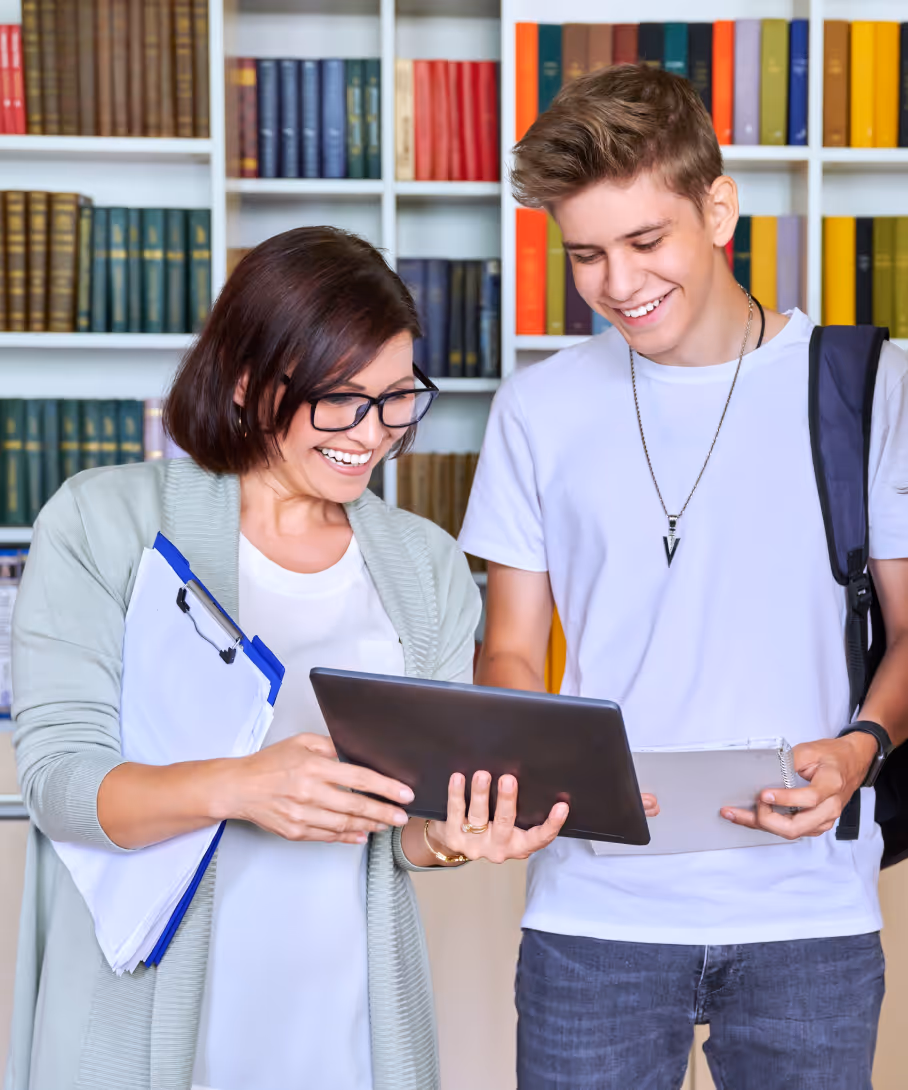 Teacher and student reviewing tablet together in library