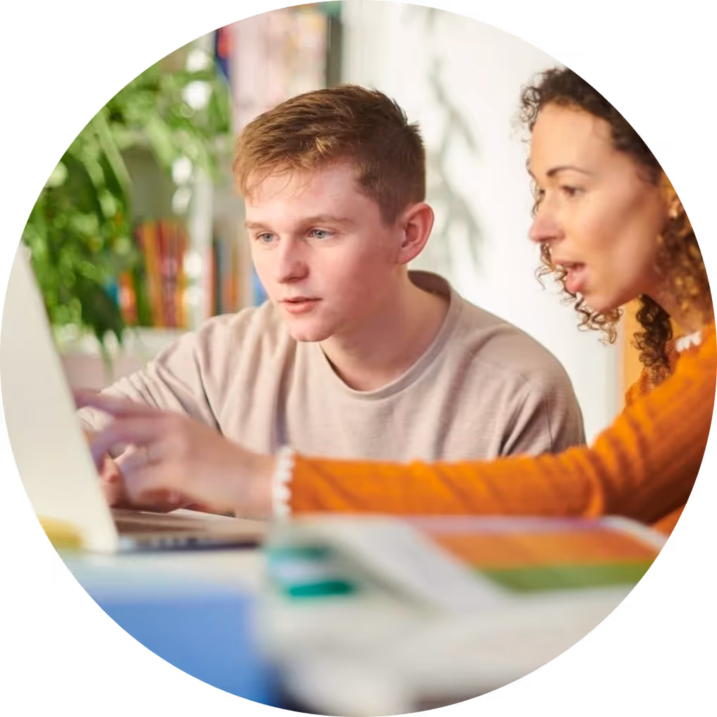 A young man and a woman working together on a laptop, focused and engaged in a learning environment.
