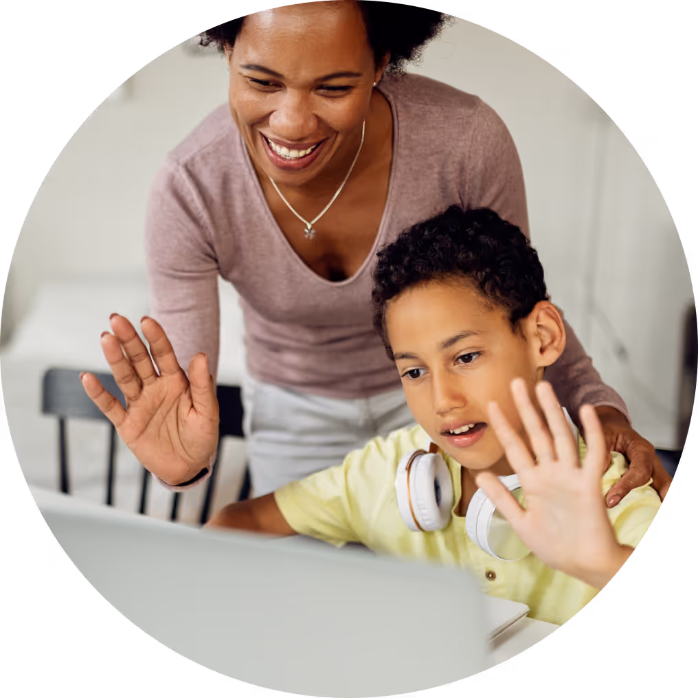 Smiling woman and child waving at a laptop during a video call