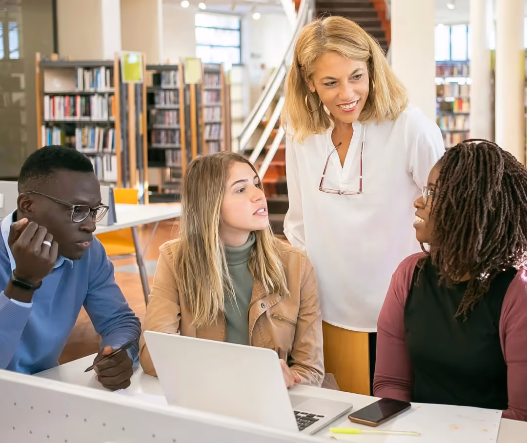 Female mentor guiding diverse students in a library